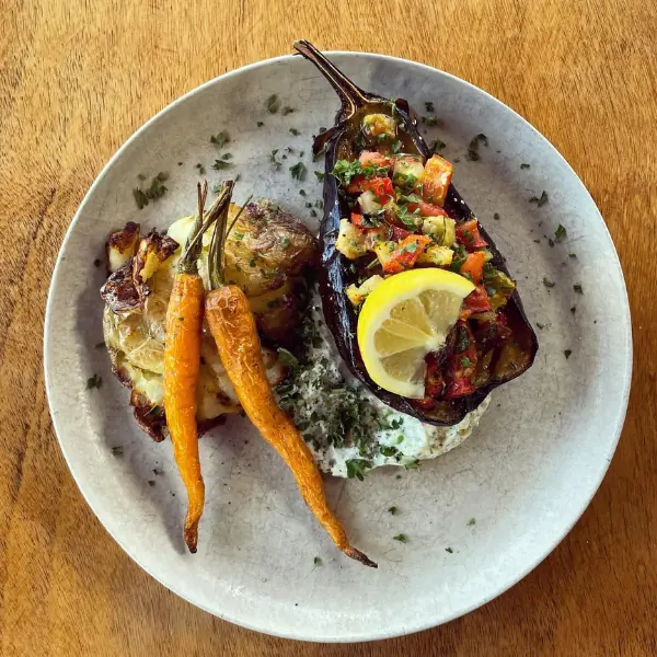Roasted aubergine with vegetable topping, lemon wedge, roasted carrots, and smashed potatoes with herb yoghurt at Volcanoview in Taranaki.